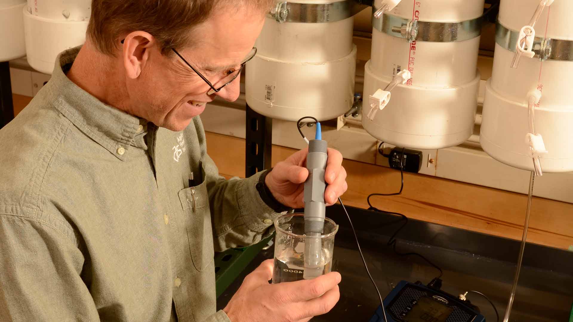scientist filling glass container and testing with probe