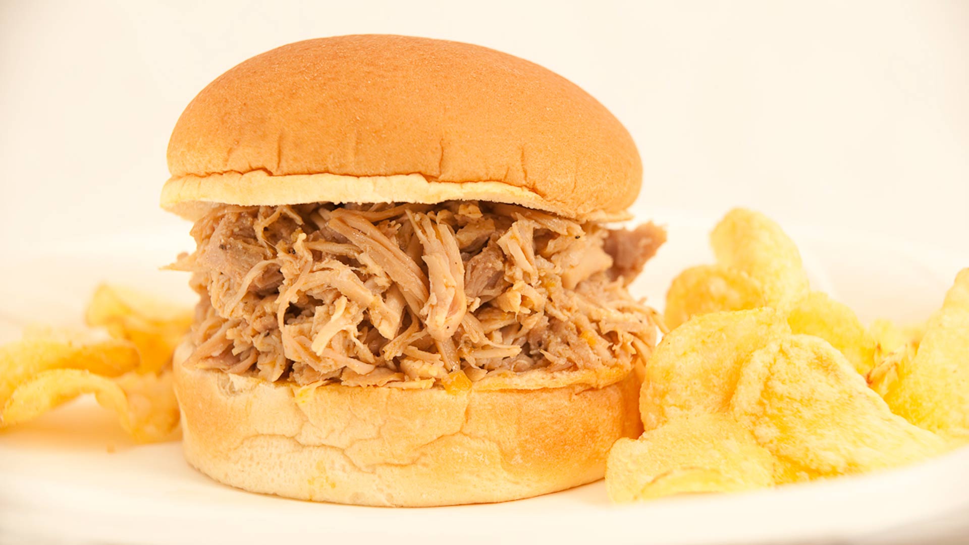 sandwich filled with pulled turkey won a plate with potato chips