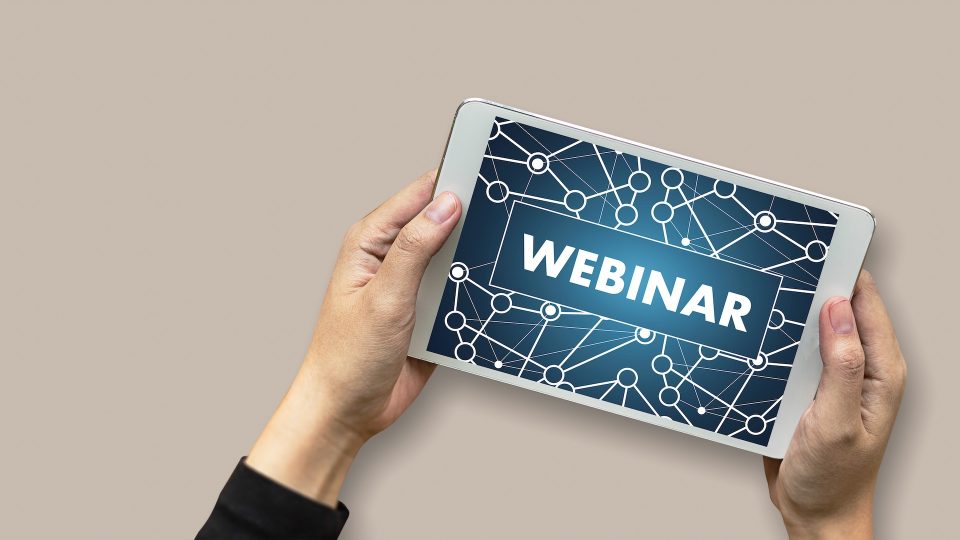 Hands holding tablet displaying the text "Webinar"